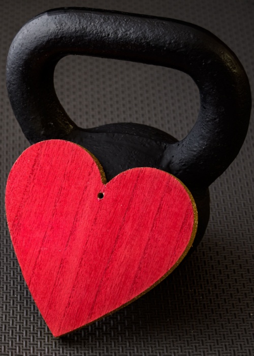 Black kettlebell on a black gym floor with large red heart