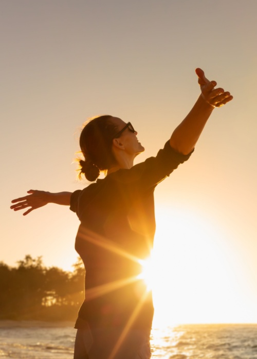 Young woman facing ocean sunset