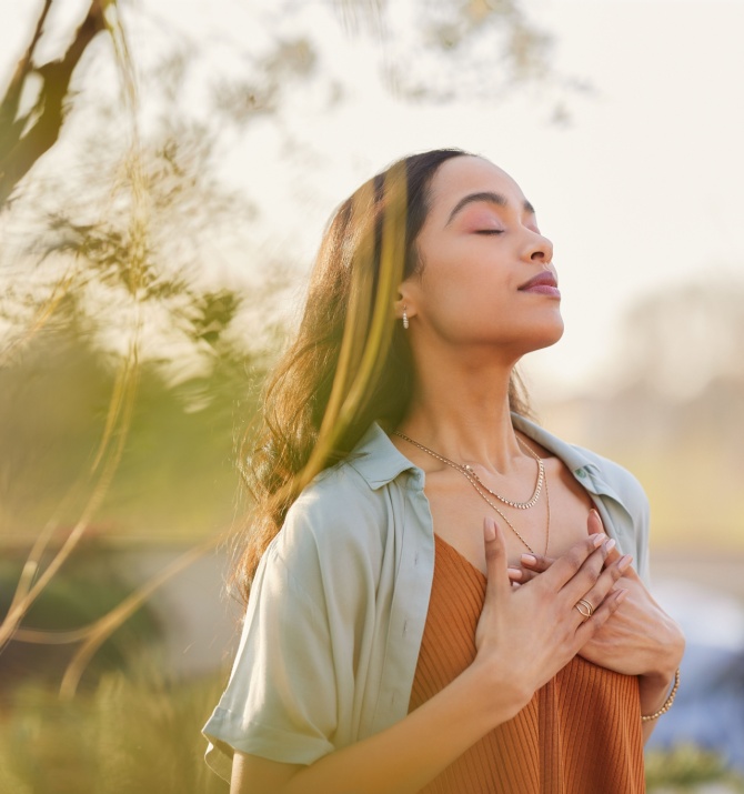 Young woman with hand on chest breathing in fresh air