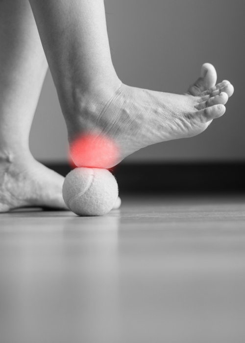 Woman massaging foot with tennis ball