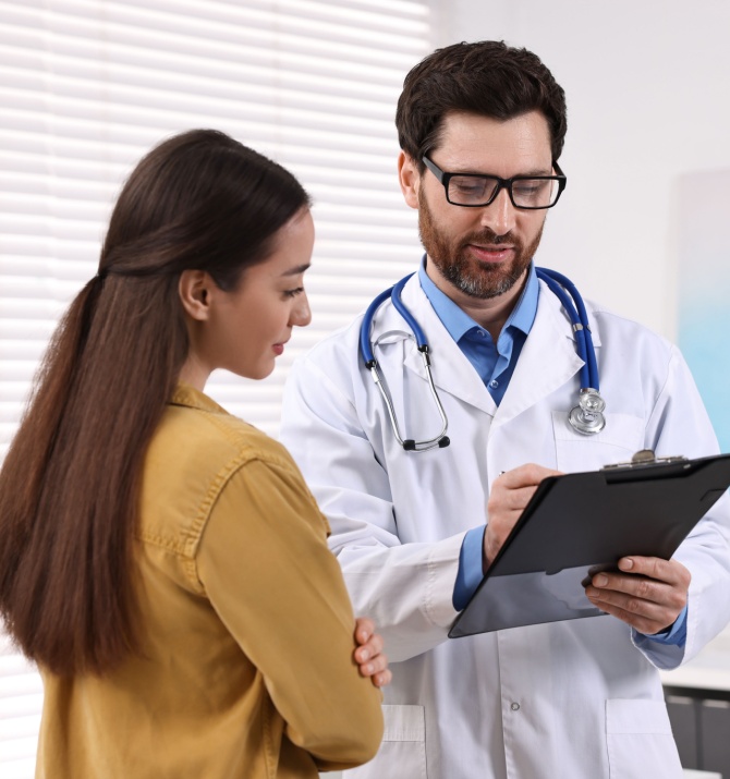 Doctor with clipboard consulting patient during appointment