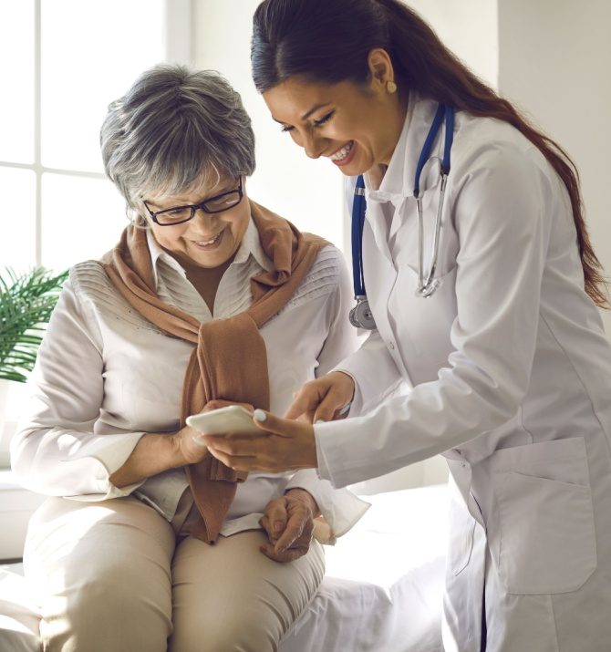 Caring doctor teaches female patient to use mobile healthcare app