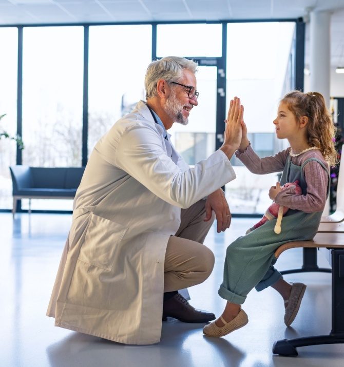 Friendly pediatrician giving high five to little patient.