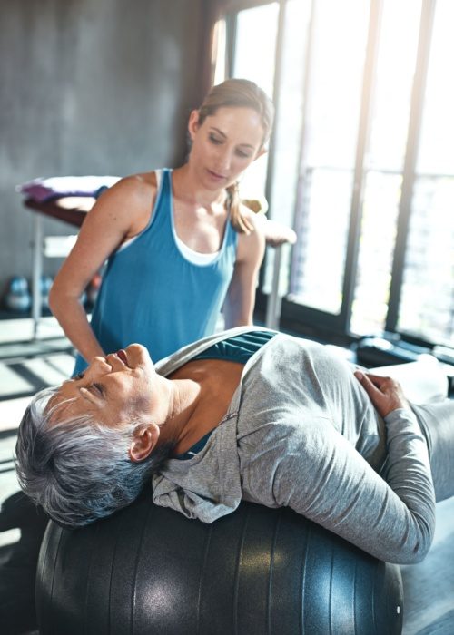 Physiotherapist, workout elderly woman with ball in clinic