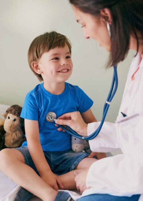 Doctor using stethoscope on happy child in hospital